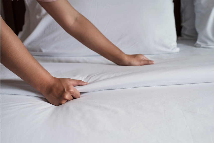 Mujer haciendo la cama en un hotel.